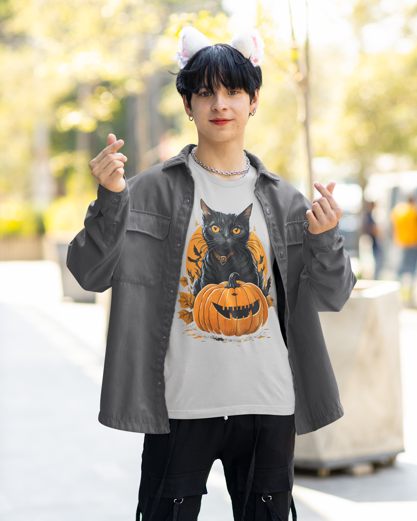 Person wearing a Halloween-themed t-shirt with a cat and pumpkin design outdoors.