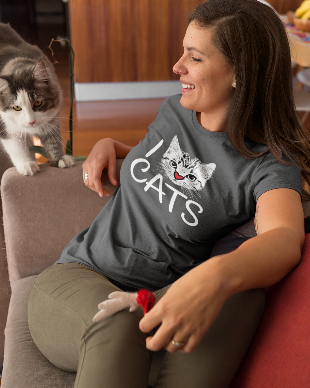 Woman sitting on a couch with a cat on her lap, wearing a shirt with a cat design.