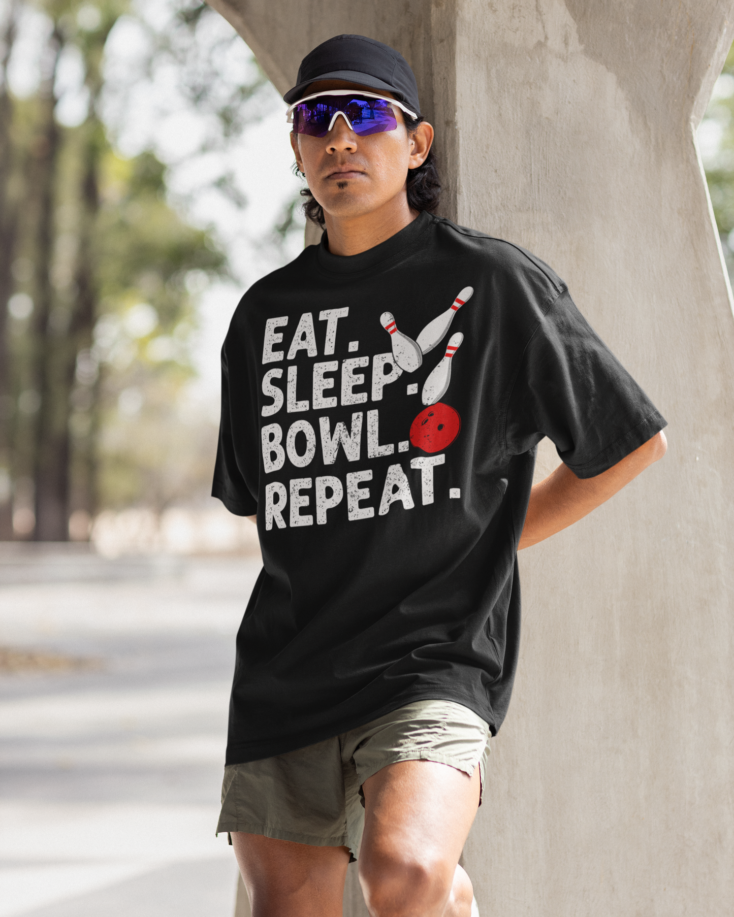 Person wearing a black t-shirt with 'Eat. Sleep. Bowl. Repeat.' text, standing outdoors.