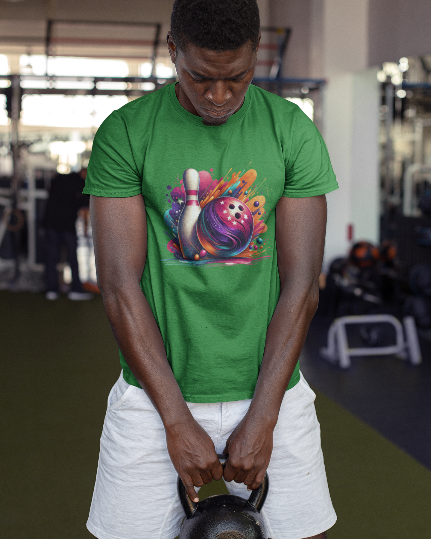 Person lifting a kettlebell wearing a green t-shirt with a colorful design in a gym setting