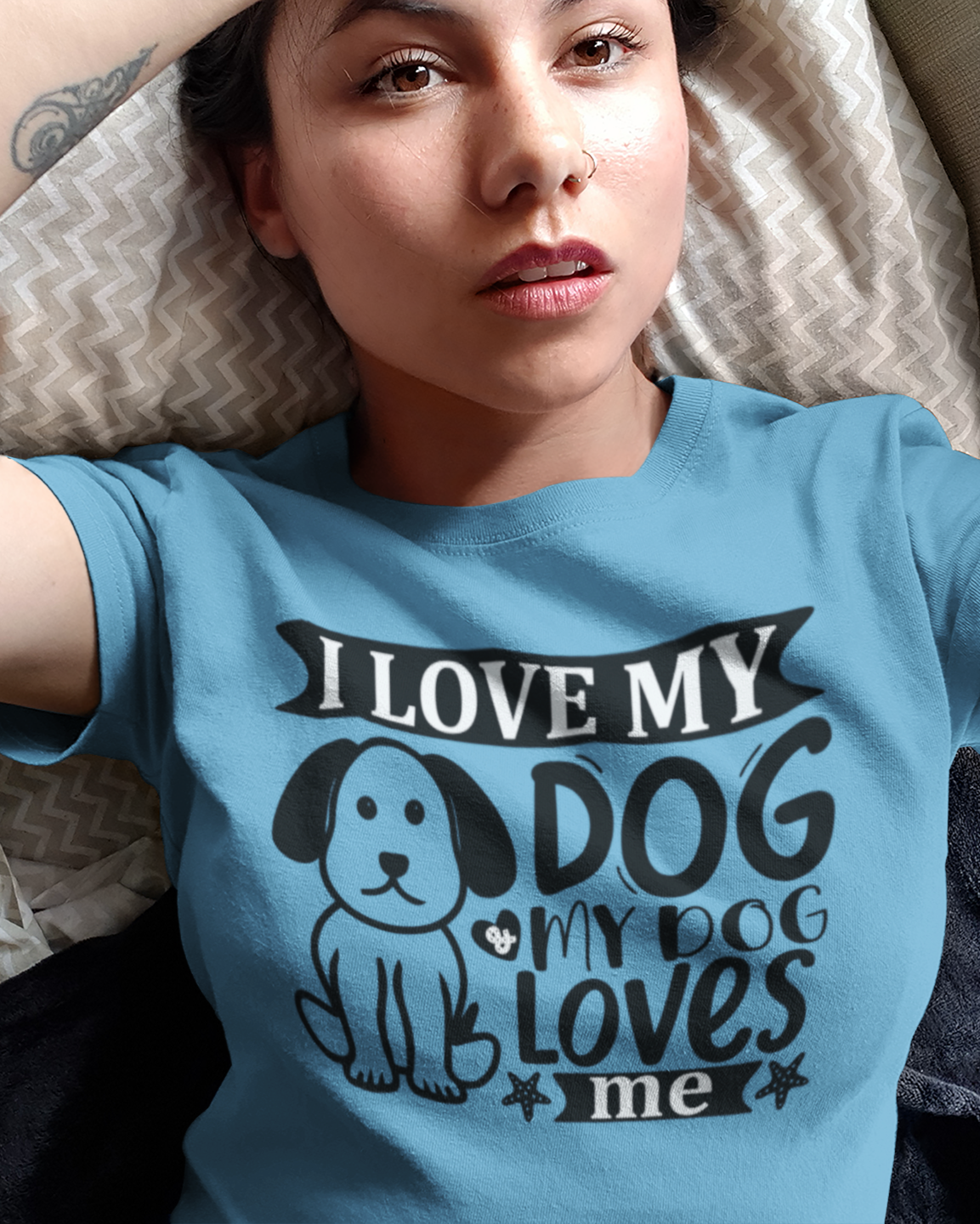 Person wearing a blue t-shirt with text lying on a bed