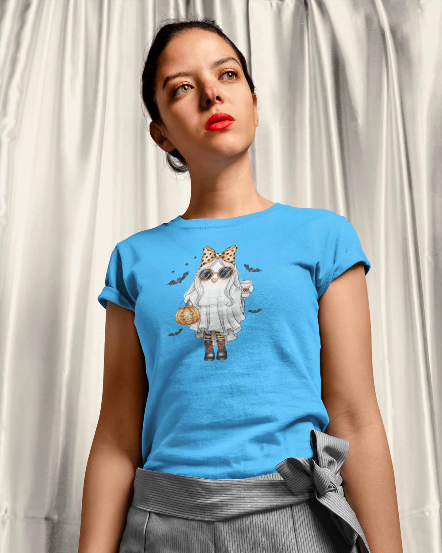 Woman wearing a blue t-shirt with a graphic design of a cat in a witch costume.