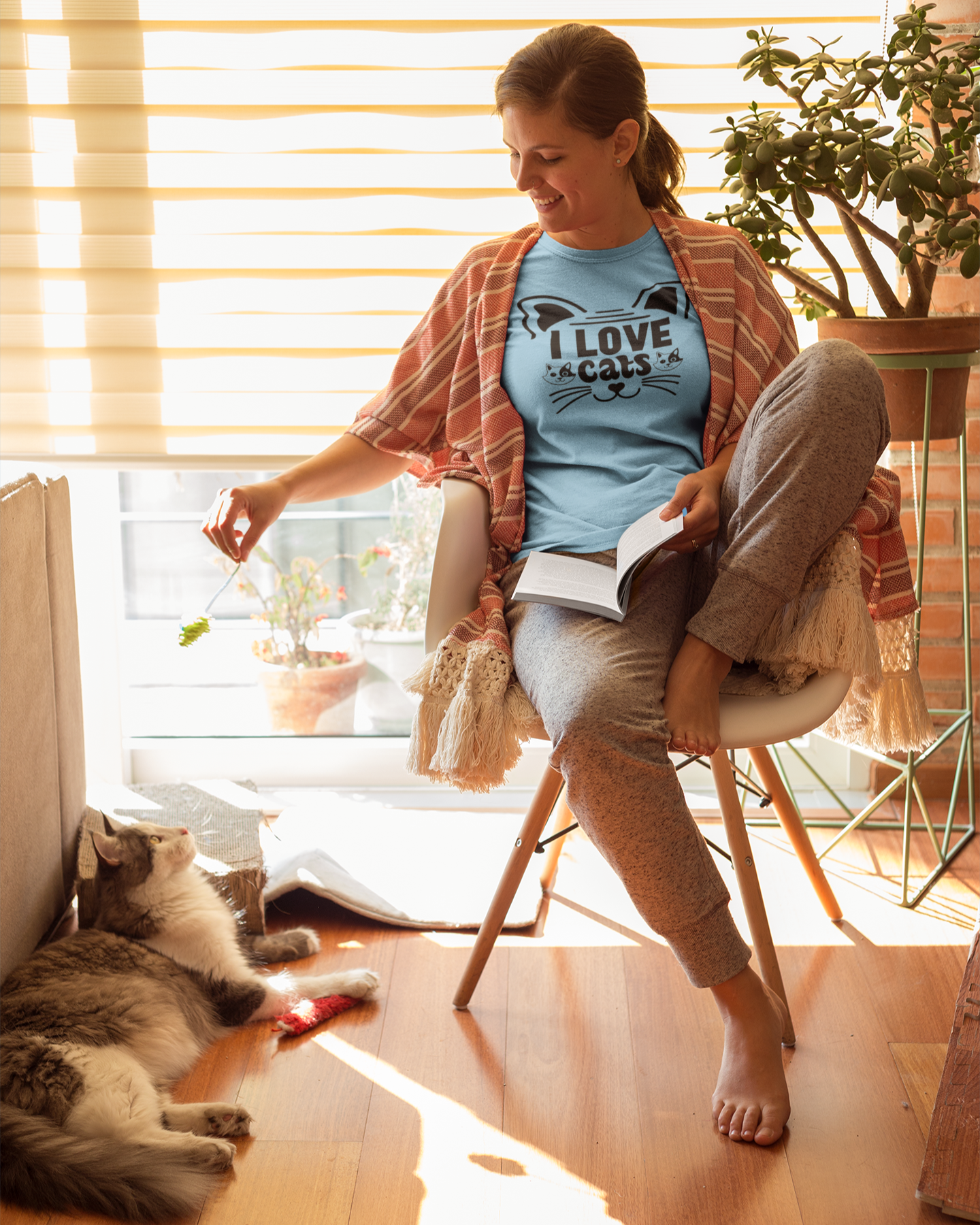 Woman sitting on a chair with a cat, holding a plant, in a bright room.