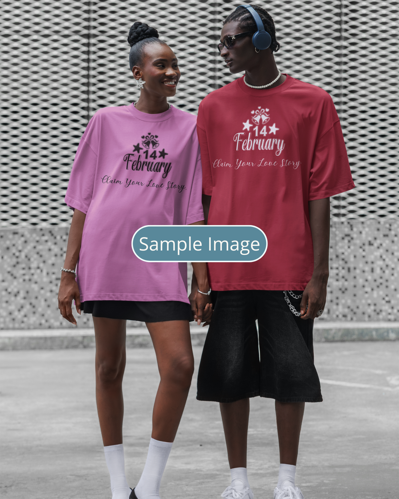 Two people wearing pink and red t-shirts with text, standing against a textured wall.