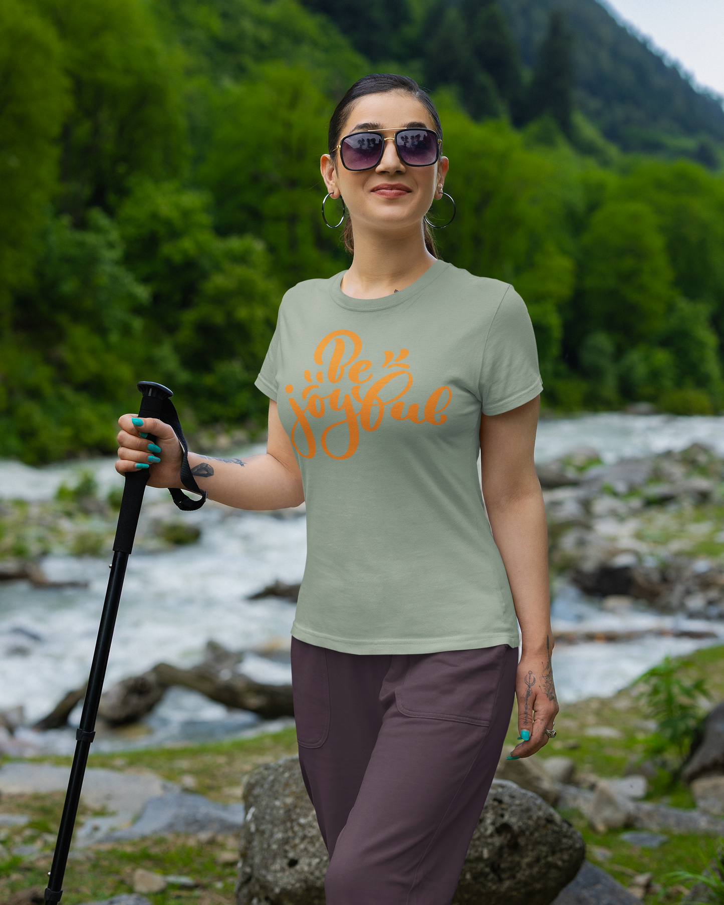 Woman hiking with sunglasses and a t-shirt with text in a scenic outdoor setting