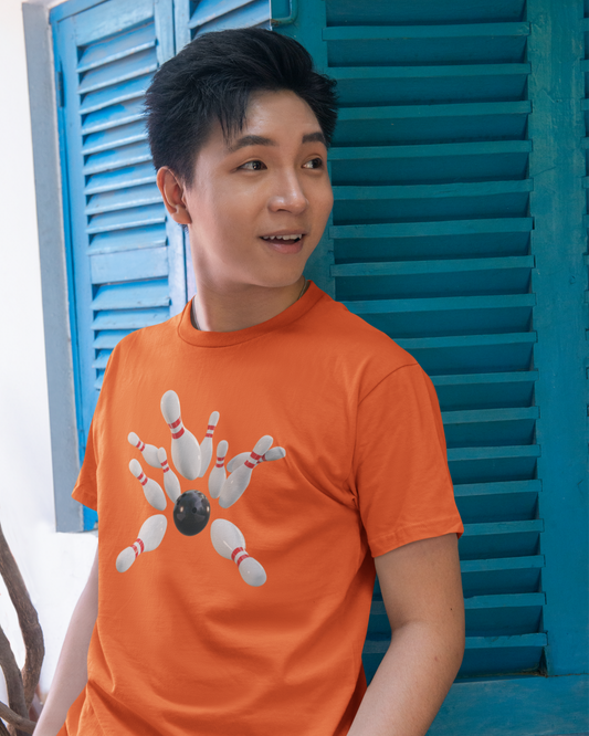 Person wearing an orange t-shirt with a bowling design in front of blue shutters.