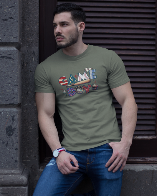 Man wearing a green t-shirt with a graphic design, leaning against a stone wall.