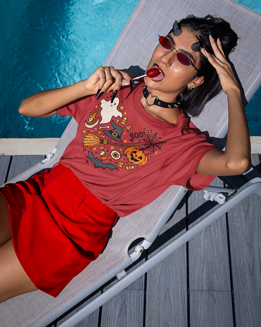 Person wearing a red Halloween-themed t-shirt and red shorts lying on a poolside lounge chair.