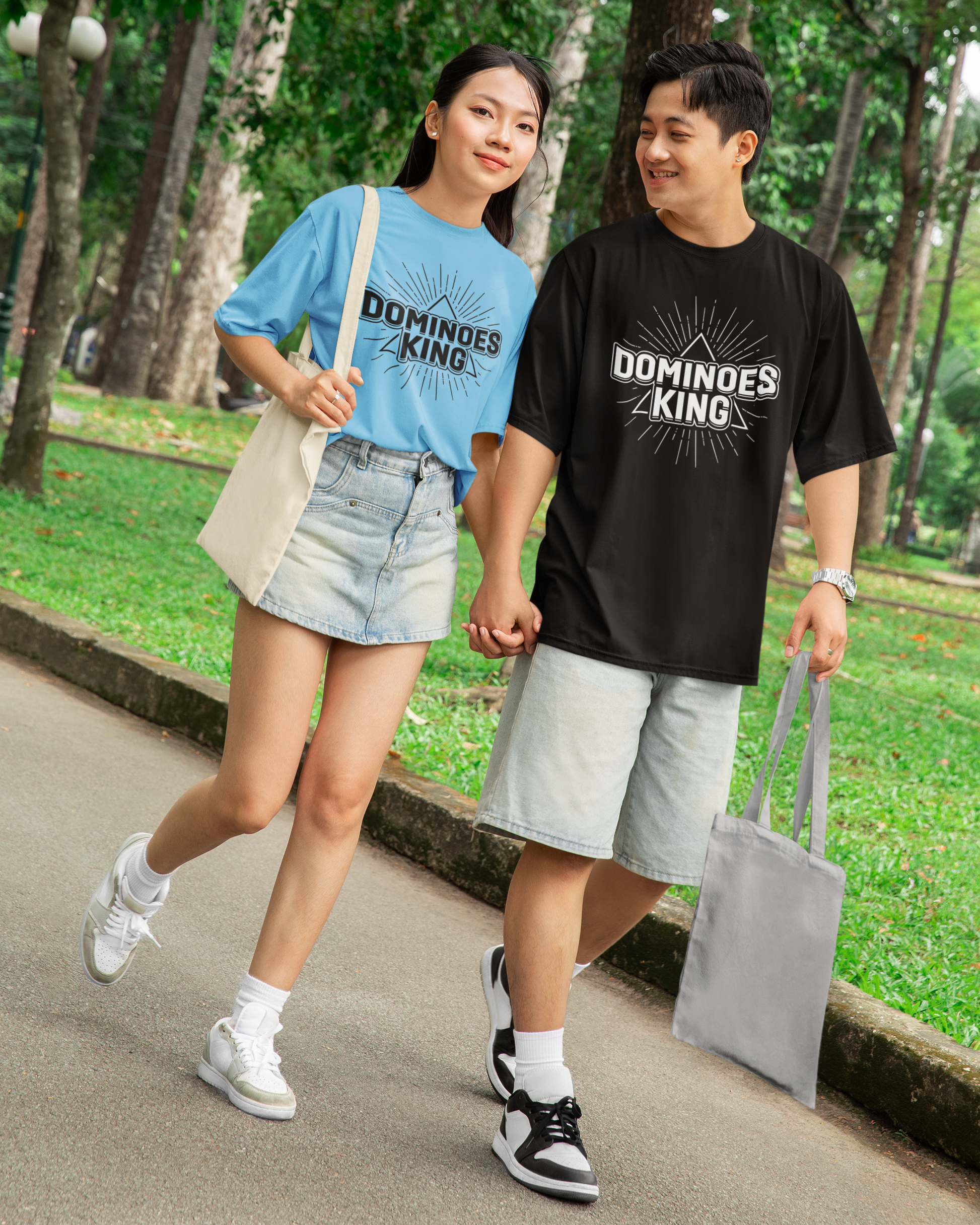 Two people walking outdoors in a park, wearing Dominies King t-shirts.