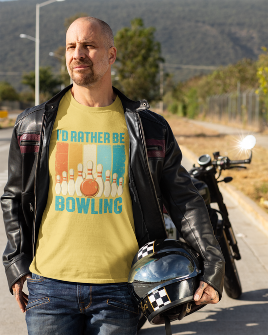 Man wearing a yellow t-shirt with a bowling design, standing next to a motorcycle on a road.