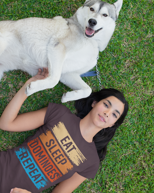 Woman lying on grass with a white dog, wearing a t-shirt with colorful text.