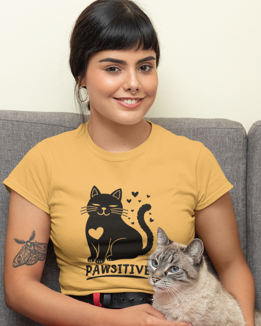 Woman wearing a yellow t-shirt with a cat design, sitting on a couch holding a cat.