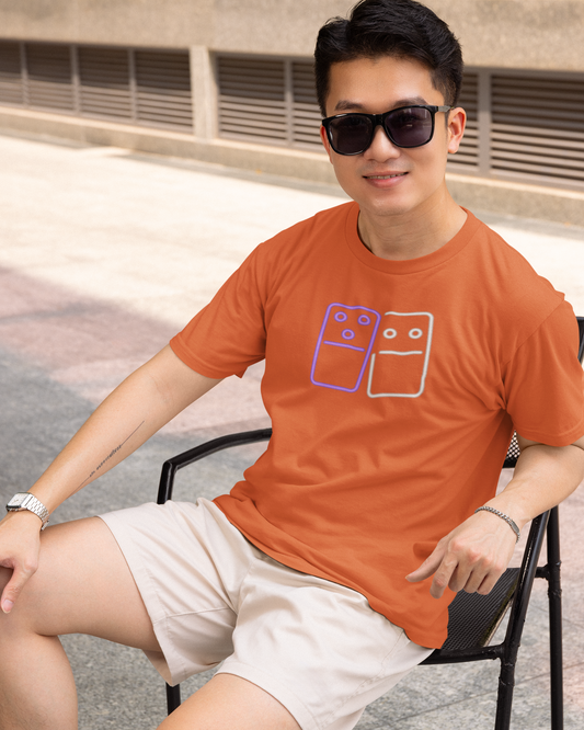 Man wearing an orange t-shirt with a graphic design, sitting outdoors.