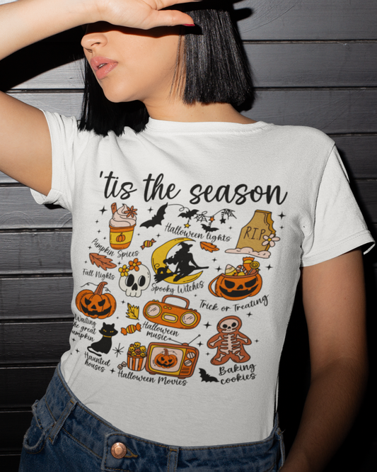 Person wearing a white t-shirt with Halloween-themed graphics and text against a dark wooden background